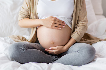 Image showing pregnant woman with bare belly sitting in bed