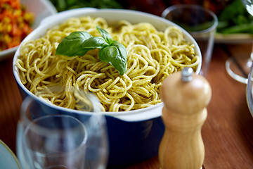 Image showing pasta with basil in bowl and other food on table