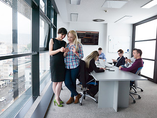 Image showing Two Elegant Women Using Mobile Phone by window in office buildin