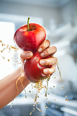 Image showing A male hand squeezes fresh juice. Pure apple juice pouring out from fruit into glass
