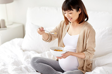 Image showing happy pregnant woman eating cereal flakes at home