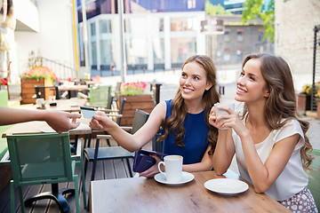 Image showing young women paying for coffee at street cafe