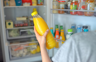 Image showing Teenage girl takes the orange juice from the refrigerator