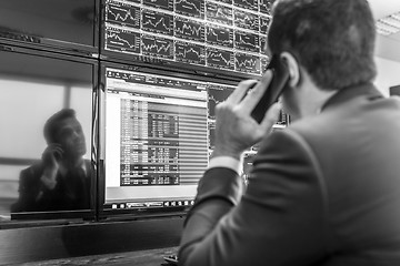 Image showing Stock trader looking at market data on computer screens.