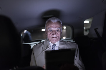 Image showing Businessman with a digital tablet sitting in the back seat of a car