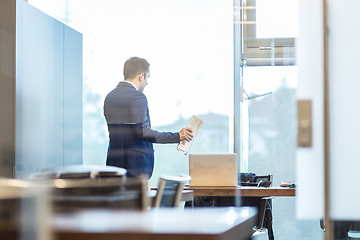 Image showing Businessman talking on a mobile phone while looking through window.