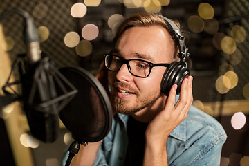 Image showing man with headphones singing at recording studio