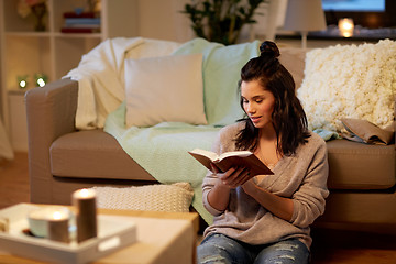 Image showing happy young woman reading book at home