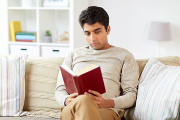 Image showing man sitting on sofa and reading book at home