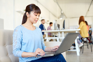 Image showing happy asian woman with laptop working at office