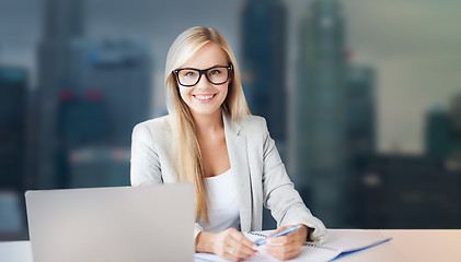 Image showing businesswoman with notepad and laptop at office