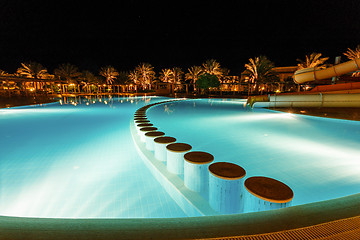 Image showing illuminated pool at night with tropical palms