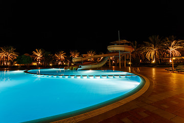 Image showing illuminated pool at night with tropical palms