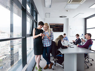 Image showing Two Elegant Women Using Mobile Phone by window in office buildin