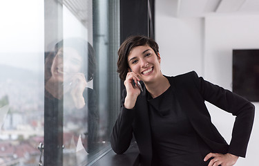 Image showing Elegant Woman Using Mobile Phone by window in office building