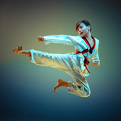 Image showing Young boy training karate on blue background