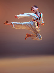 Image showing Young boy training karate on blue background