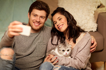 Image showing happy couple taking selfie by smartphone at home