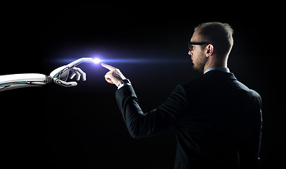 Image showing robot and human hand flash light over black