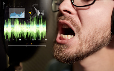 Image showing man with headphones singing at recording studio