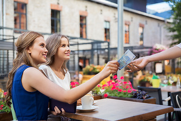 Image showing young women paying for coffee at street cafe