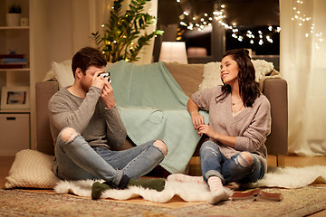 Image showing happy couple with camera photographing at home