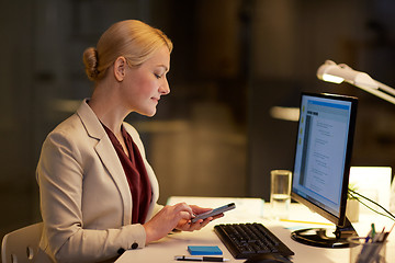 Image showing businesswoman with smartphone at night office