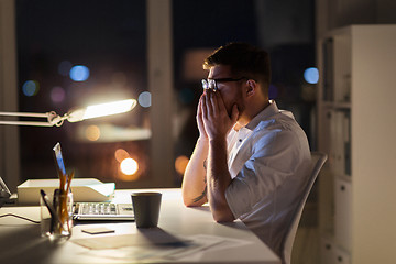 Image showing tired businessman with laptop at night office