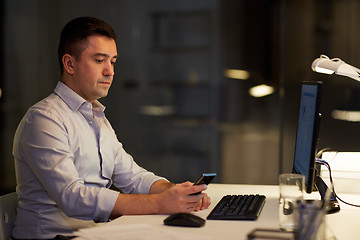 Image showing man with smartphone working late at night office