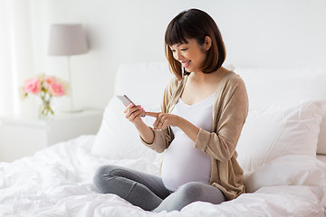 Image showing pregnant woman with smartphone in bed at home