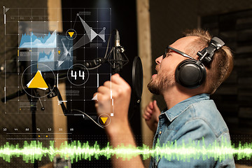 Image showing man with headphones singing at recording studio