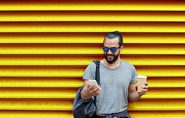 Image showing man with coffee cup and smartphone over wall