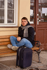 Image showing Young man sitting in winter on a bench