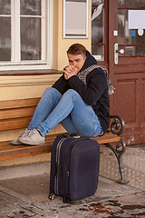 Image showing Young man sitting in winter on a bench