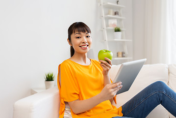 Image showing happy asian woman with tablet pc and apple at home