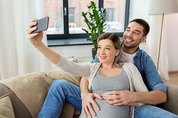 Image showing man and pregnant woman taking selfie at home