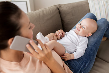 Image showing mother with baby calling on smartphone at home