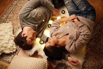 Image showing happy couple with garland lying on floor at home