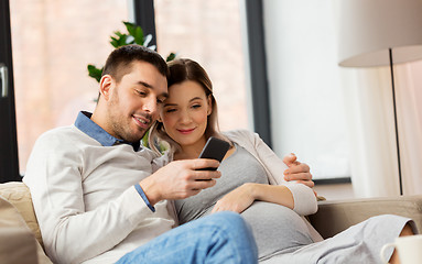 Image showing man and pregnant wife with smartphone at home