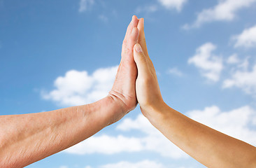 Image showing close up of senior and young woman hands over sky