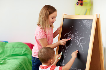 Image showing happy kids drawing on chalk board at home