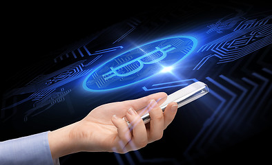 Image showing close up of hand with smartphone and bitcoin