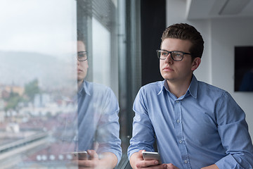 Image showing Businessman Standing In A Modern Building Near The Window With P