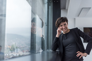 Image showing Elegant Woman Using Mobile Phone by window in office building