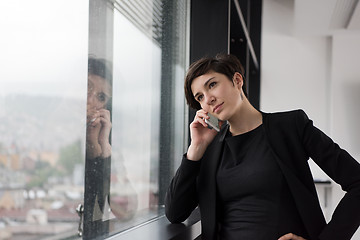 Image showing Elegant Woman Using Mobile Phone by window in office building