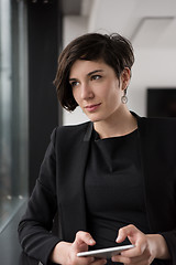 Image showing Elegant Woman Using Mobile Phone by window in office building