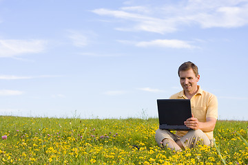 Image showing Man sitting with laptop computer in a meadow