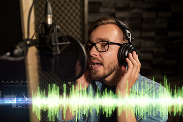 Image showing man with headphones singing at recording studio