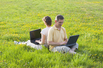 Image showing Coupe sitting with laptops in a meadow