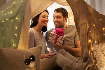 Image showing happy couple with gift box in kids tent at home